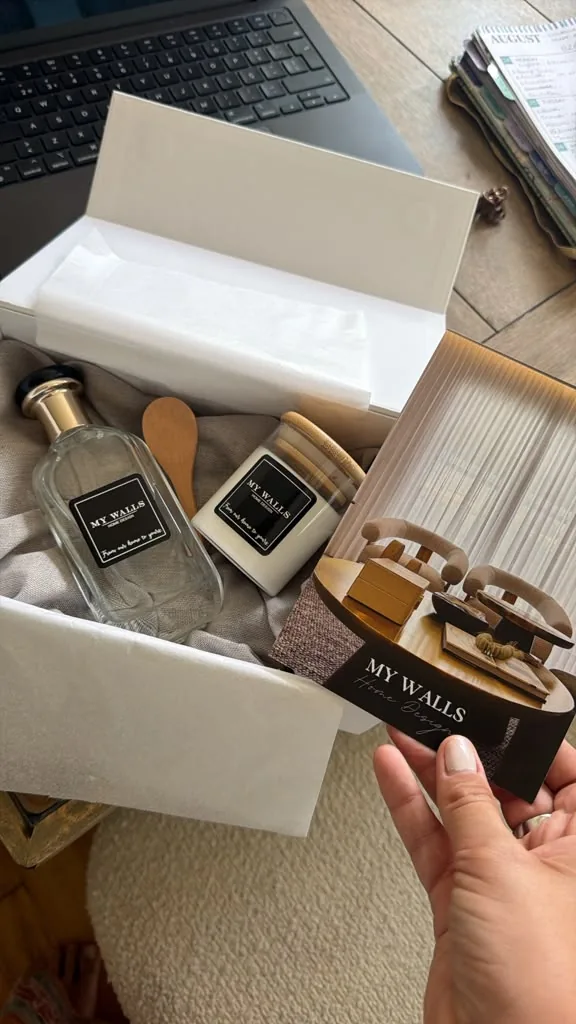 Open gift box with a branded fragrance bottle, a candle and a card.