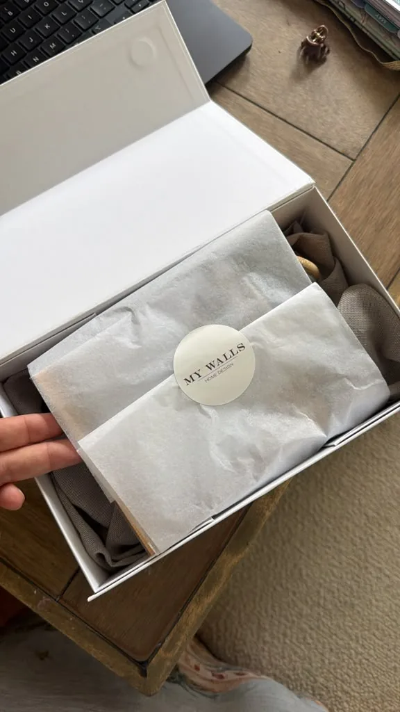 Open box with tissue paper sealed by a round My Walls sticker.